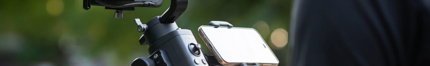 En mann holder en gimbal med speilløst kamera.